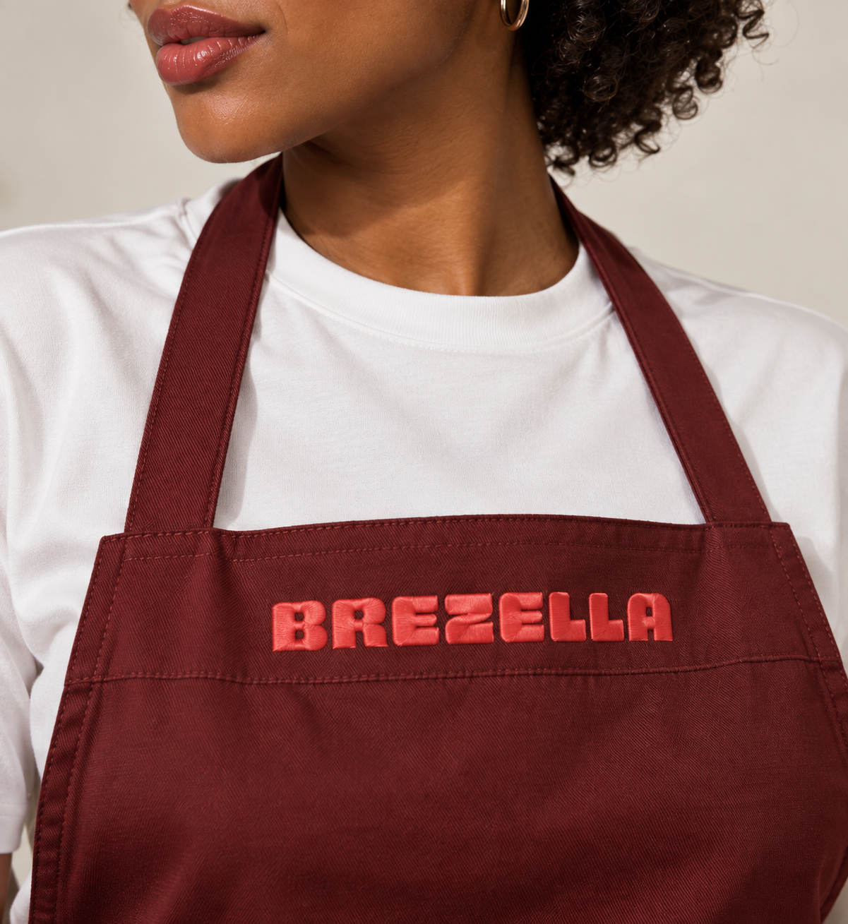 Brezella-Schürze mit korallroter Schrift auf dunklem Stoff.
